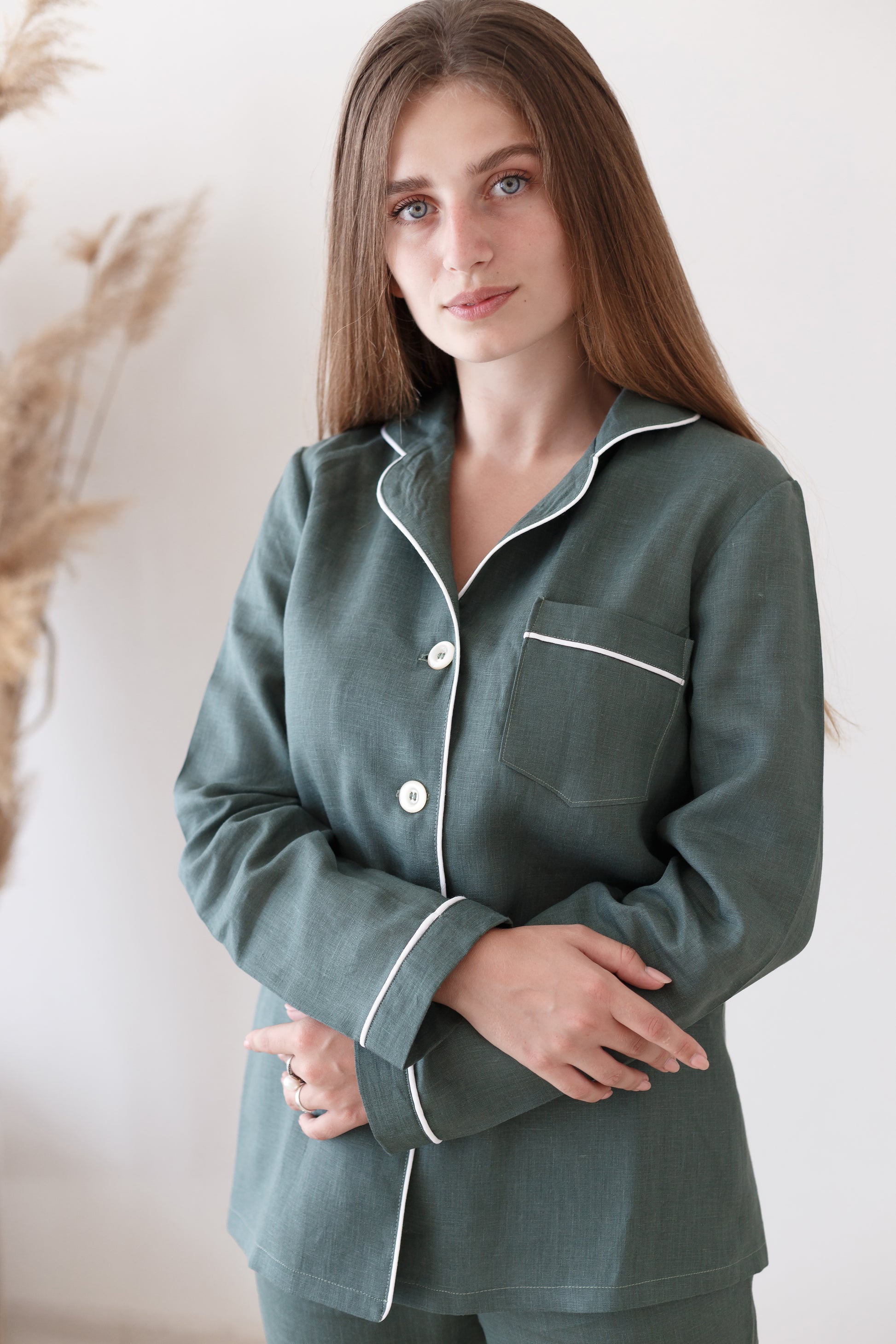 Close-up of green linen pajama top with collar, buttons, and white piping detail