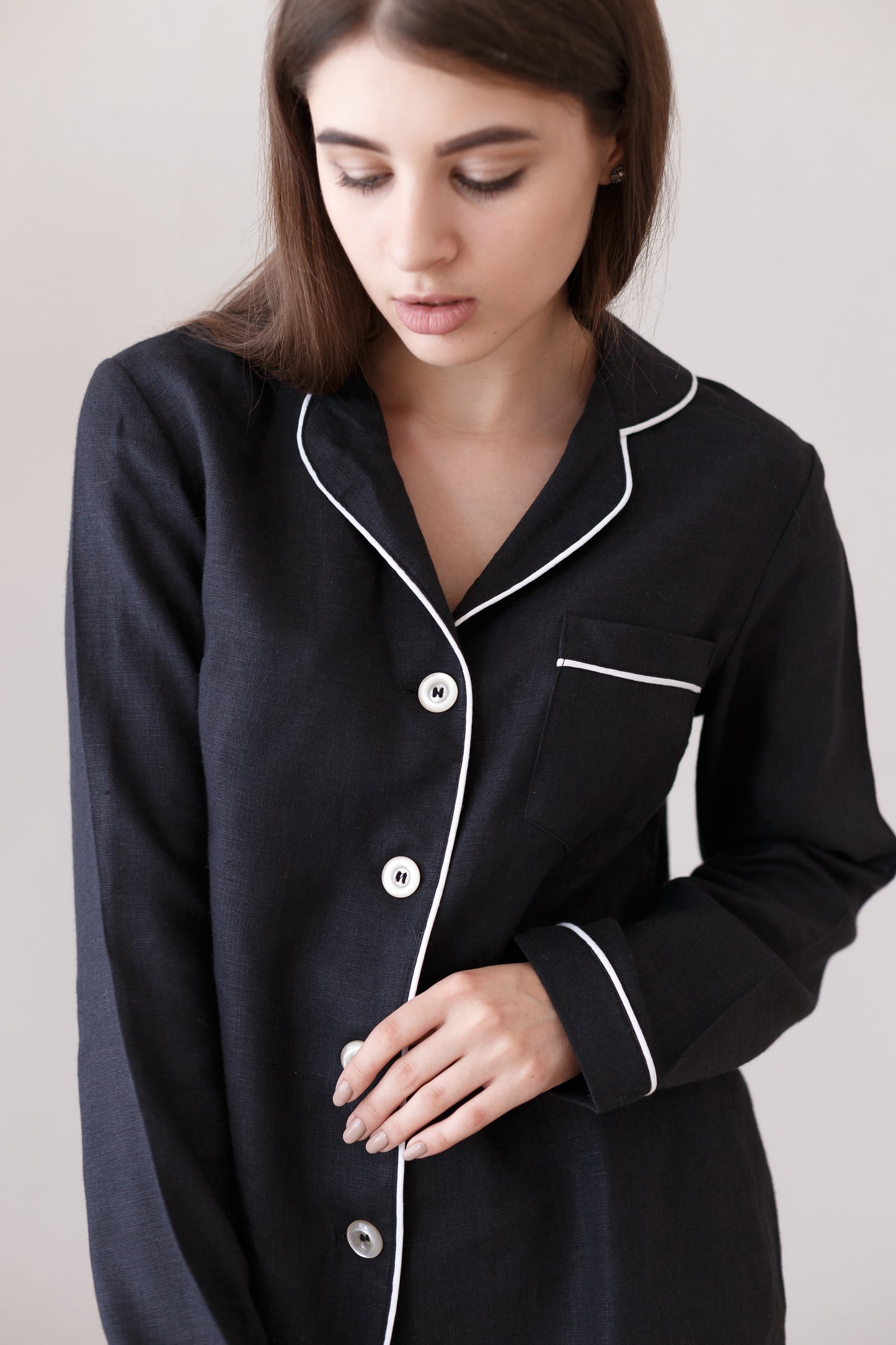 Close-up of black linen pajama top with collar, buttons, and white piping detail